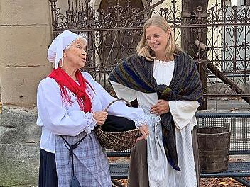 Die mitteilsamen Marktfrauen sind am Marktbrunnen im Gespräch.