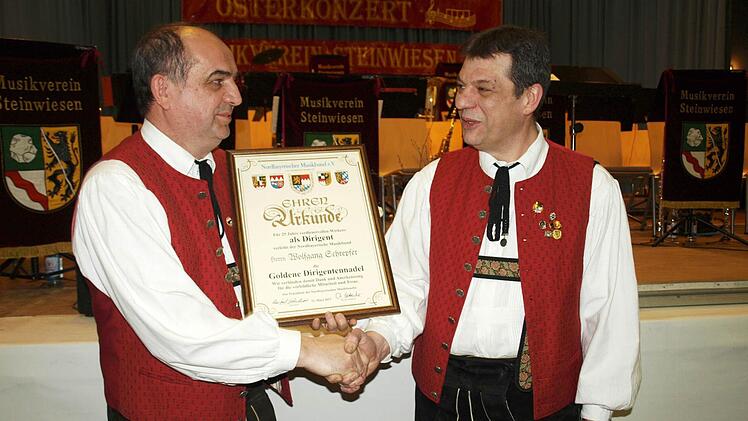 Stolz überreicht stellv. Bezirksvorsitzender Thomas Kolb (links) die Urkunde für 25 Jahre Dirigent an Wolfgang Schrepfer (rechts).