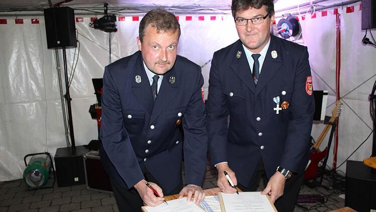 Klaus Killinger (l.) von der Dachstadter Feuerwehr und Heinz Igel aus Pommer unterzeichnen den Vertrag. fra-press