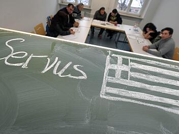 Auf eine Tafel in einem Unterrichtsraum in Nürnberg ist das Wort «Servus» neben die griechische Nationalflagge geschrieben. Hier erhalten aus Griechenland eingewanderte Bürger Deutschunterricht. Trotz Kritik und Spott von allen Seiten hält die CSU-Führung an ihren Sprachvorgaben für Ausländer in Deutschland fest. Foto: David Ebener/dpa