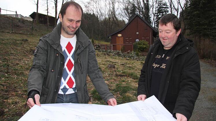 Der Vorsitzende des Frankenwaldvereins Wartenfels, André Hümmer, und sein Stellvertreter Klaus Gareis mit den ersten Planungen für den Neubau. Dort, wo einst der Gemeindewald war, soll eine Lagerstätte aus Holz errichtet werden. Foto: Sonja Adam