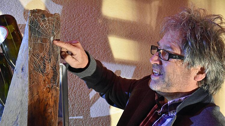 Hannes Betz  erklärt, wie er ein echtes Spinnennetz "eingefangen" und auf einem seiner Kunstwerke versiegelt hat. Foto Ulrike Langer