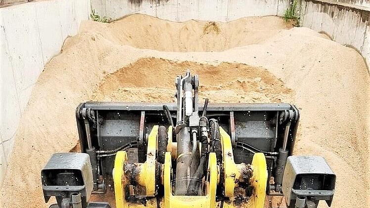 Mit einem kleinen Bagger wird Sand zur Abf&uuml;llanlage gebracht.