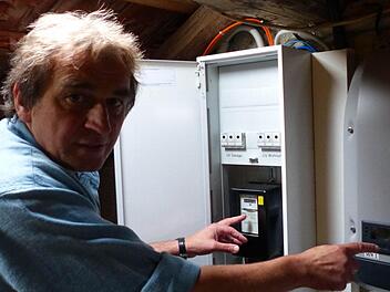 In seinem Dachboden zeigt der Energieberater Günter Lieberth seinen Stromzähler sowie den für die Solaranlage installierten Wechselrichter. Der Experte möchte möglichst viele Hausbesitzer ermutigen, seinem Beispiel zu folgen. Foto: Manfred Wagner