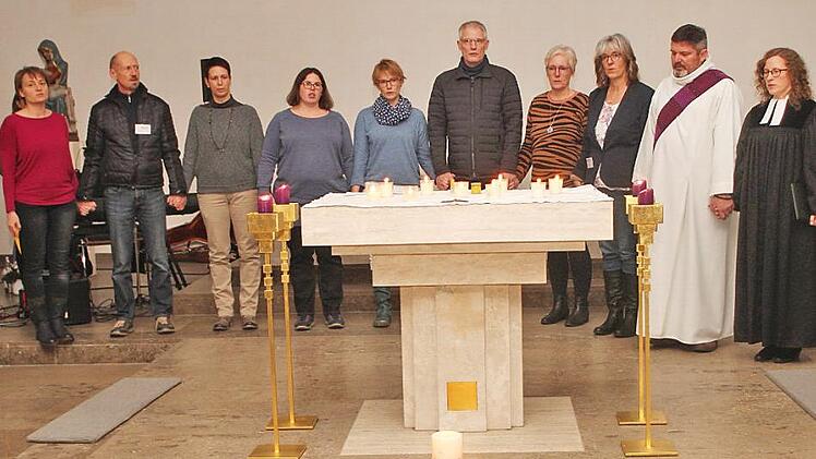 Die Frauen und Männer der Arbeitsgruppe "Sternenkinder" zusammen mit Pfarrerin Sarah Schimmel und Diakon Joachim Stapf (von rechts): Sie stehen vereint um den Altar mit den leuchtenden Kerzen für die verstorbenen Kinder.  Fotos: Günther Geiling