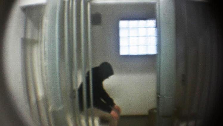 Mehrmals in der Nacht kontrollieren die Beamten der Polizei Höchstadt, was die Insassen in der Arrestzelle machen. Um sie nicht zu stören, schauen die Polizisten dann oft nur durch den Spion der Tür. Hier sitzt unser Praktikant Kilian Schmidt nur "Probe". Foto: Sebastian Martin
