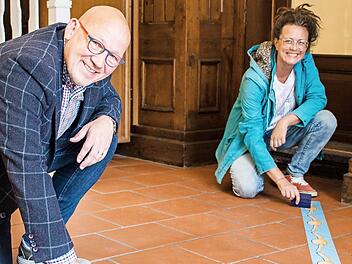Der Betriebsleiter von Coburg Marketing, Horst Graf und Diplomdesignerin Katrin Planner legen letzte Hand an die Musterbeklebung im Eingangsbereich der Coburg Tourist-Info, die am Montag wieder für Kunden öffnet. Foto: Michael Selzer