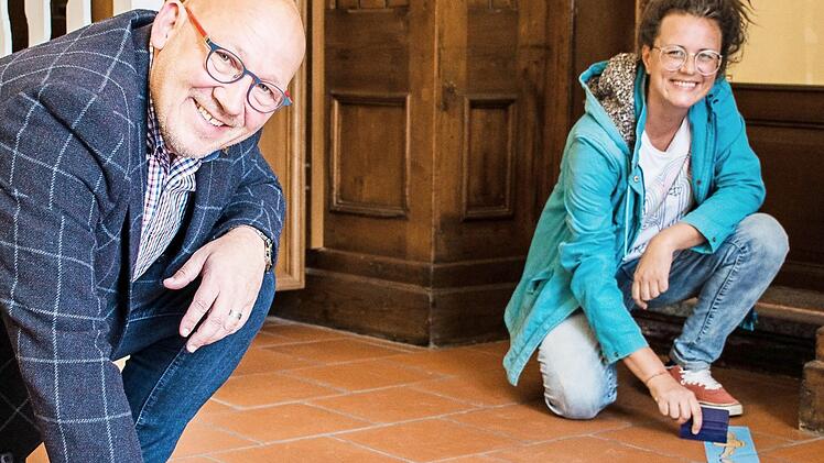 Der Betriebsleiter von Coburg Marketing, Horst Graf und Diplomdesignerin Katrin Planner legen letzte Hand an die Musterbeklebung im Eingangsbereich der Coburg Tourist-Info, die am Montag wieder für Kunden öffnet. Foto: Michael Selzer