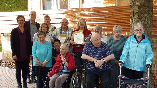 Seit 30 Jahren arbeiten die Eheleute Martina und Harald Kalnischkies (Bildmitte mit Urkunden)im Wohnheim der Lebenshilfe in Bad Kissingen. Bei einer Feierstunde wurden die beiden P&auml;dagogen, die damals die Anf&auml;nge des Hauses in der Bad Kissinger Hartmannstra&szlig;e mitgestaltet haben, f&uuml;r ihren Einsatz und die langj&auml;hrige Treue zur Lebenshilfe Bad Kissingen geehrt.Im Bild die Bewohner  mit der Aufsichtsratsvorsitzenden Monika Fella (ganz links), Vorstand Alex Iffert (zweiter von links) und Wohnheim...