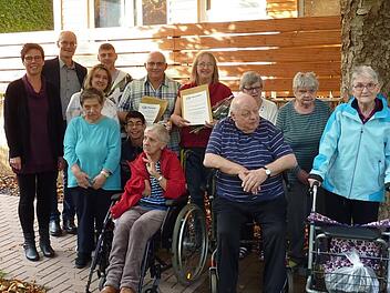 Seit 30 Jahren arbeiten die Eheleute Martina und Harald Kalnischkies (Bildmitte mit Urkunden)im Wohnheim der Lebenshilfe in Bad Kissingen. Bei einer Feierstunde wurden die beiden P&auml;dagogen, die damals die Anf&auml;nge des Hauses in der Bad Kissinger Hartmannstra&szlig;e mitgestaltet haben, f&uuml;r ihren Einsatz und die langj&auml;hrige Treue zur Lebenshilfe Bad Kissingen geehrt.Im Bild die Bewohner  mit der Aufsichtsratsvorsitzenden Monika Fella (ganz links), Vorstand Alex Iffert (zweiter von links) und Wohnheim...
