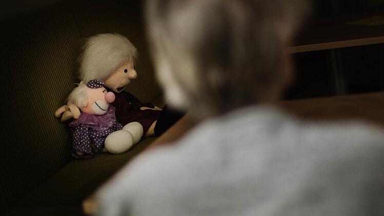 Die beiden Puppen, die vom Sofa aus in den nächtlichen Speiseraum blicken, passen zu dem kindlichen Verhalten, das manch demenziell erkrankter Mensch zeigt. Fotos: Steffens