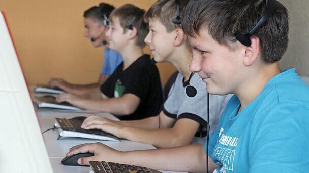 Gerald (von rechts), Lukas, André und Pascal haben das Headset auf und arbeiten an den neuen Geräten.