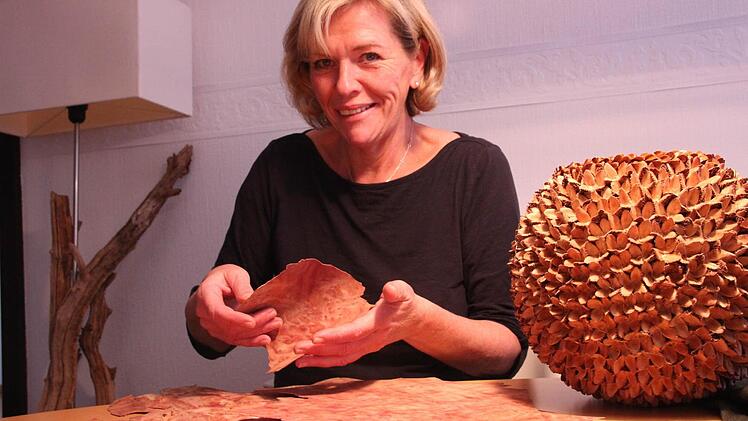 Martina Straub zeigt das Furnierholz, das den stabilen Rahmen für diese Kugel aus Bucheckern bildet. Foto: <?Fotos:?><?_Fotos:?>Heike Beudert