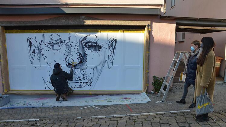 Eines von 24 Fenstern, die in der Innenstadt ab heute zu besichtigen sind. Gestern war Künstler Julian Vogel am Fenster der Eisdiele am Marktplatz noch am Arbeiten, rechts Judith Jochmann und Simira Tang vom Stadtmarketing.  Fotos: Bernhard Panzer