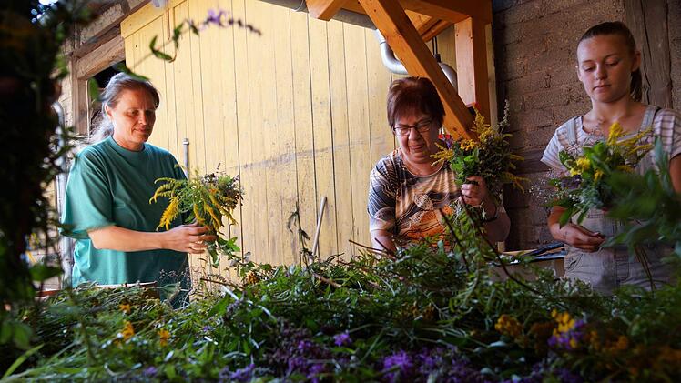 Marietta Panhans (Mitte) bindet zusammen mit anderen Frauen Kräutersträuße für Mariä Himmelfahrt. Foto: Arkadius Guzy