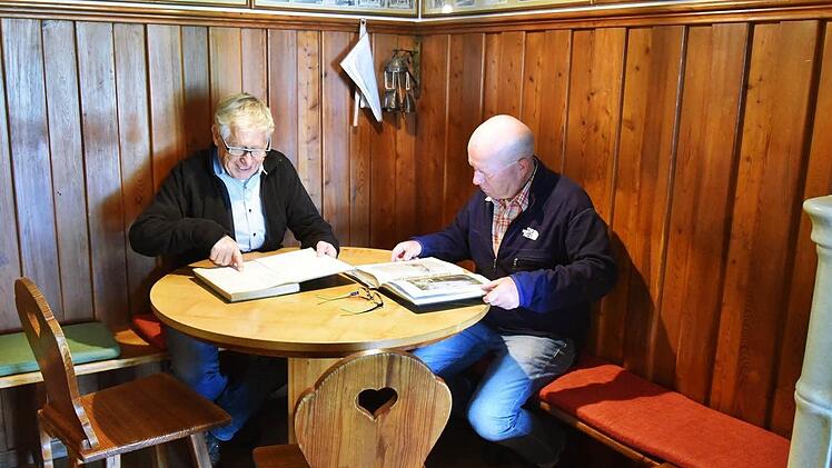 Die Vorsitzenden des Thüringerwald-Vereins Dieter Schubert und Helmut Völk blättern in der gemütlich Wirtsstube in den alten Hüttenbüchern, die Erinnerungen wecken. Foto: Gabi Arnold