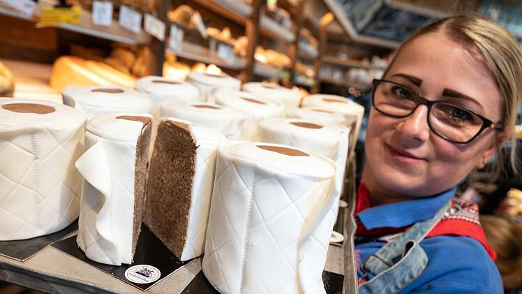Eine Verkäuferin der Bäckerei Schürener Backparadies zeigt im Verkaufsraum ein Blech mit runden Marmorkuchen, die mit Fondant umwickelt wie Toilettenpapier-Rollen aussehen. Der Klopapier-Kuchen von Bäcker Kortüm ist in der Corona-Krise zu einem ·Bestseller· geworden. Foto: Bernd Thissen/dpa