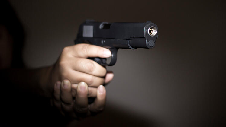 Hand hält Waffe