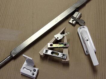 Türen können gesichert werden. Die lange Stange oben zeigt einen Teleskopriegel - eine einfache Lösung für Kellertüren, außerdem eine Fenstersicherung gegen das Aufhebeln, Schließbleche für Tür und Fenster, ein Schlüssel mit gesichertem, geschützten Profil und Abtastsperre sowie ein weißer Alarmfenstergriff. Foto: Johanna Blum