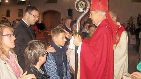 Maximilian Greser wird von Erzbischof Ludwig Schick gefirmt. Firmpate des Firmlings ist Holger Fiedler, Priester in Hof. Foto: Paul Hader