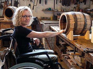 Die Kulturwissenschaftlerin Simone Doll-Gerstendörfer hat intensiv am Inklusionsprojekt des Fladunger Freilandmuseums mitgewirkt. Mit einem Rollstuhl testet sie, ob die Schauobjekte der ehemaligen Sulzthaler Büttnerei für behinderte Besucher gut erreichbar sind. Foto: Gerhard Fischer