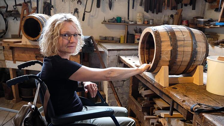 Die Kulturwissenschaftlerin Simone Doll-Gerstendörfer hat intensiv am Inklusionsprojekt des Fladunger Freilandmuseums mitgewirkt. Mit einem Rollstuhl testet sie, ob die Schauobjekte der ehemaligen Sulzthaler Büttnerei für behinderte Besucher gut erreichbar sind. Foto: Gerhard Fischer