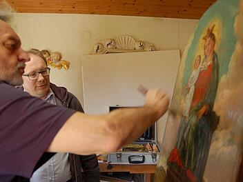 Den letzten Firnis-Anstrich trägt Reinhold Müller im Beisein von Pfarrer Thomas Eschenbacher auf. Das Bild ist nun wieder konserviert. Foto: Barbara Oschmann