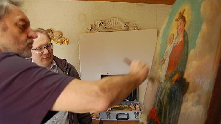 Den letzten Firnis-Anstrich trägt Reinhold Müller im Beisein von Pfarrer Thomas Eschenbacher auf. Das Bild ist nun wieder konserviert. Foto: Barbara Oschmann