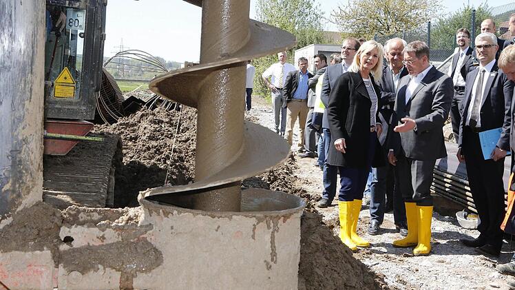 Ein riesiger Bohrer gräbt Löcher an den Stellen in den Untergrund, an denen Spundwände in den Boden getrieben werden. Unser Bild zeigt Umweltministerin Ulrike Scharf bei der Baustellen-Besichtigung mit OB Henry Schramm.