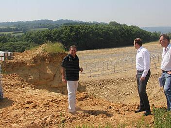 Vom einstigen Steinbruch ist nicht mehr viel zu erkennen. Die ersten Pfähle für den Bürgersolarpark wurden gesetzt. Im Bild (von links): Bürgermeister Norbert Gräbner, der Vorsitzende der Deutschen Bürger-Energie, Mario Fürst, und Geschäftsleitender Beamter Gerd Wich-Heiter. Foto: Veronika Schadeck