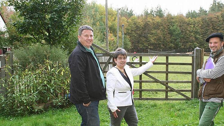 Markus Blum, Christine Spahn und Nicolas Sportelli (v.l.): Hinter dem Wald in der Bildmitte wären die Windräder zu sehen, und im Grün steht Blums Haus. Foto: Evi Seeger