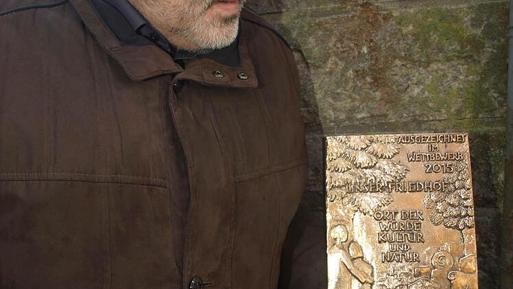 Diese Plakette, die Bürgermeister Franz Kuhn in der Hand hält, wird am Eingang zum Waldfriedhof angebracht. Foto: Stefan Geiger