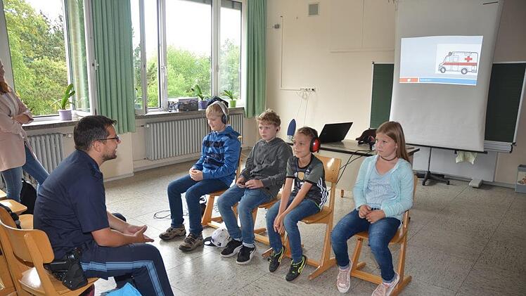 Musik über Ohrenknopf oder Kopfhörer vom Smartphone hören ist wie gehörlos am Straßenverkehr teilzunehmen. Dies demonstrierte PHK Verkehrserzieher Heiko Sesselmann mit Geräuschsimulationen (Leinwand im Hintergrund) von verschiedenen Fahrzeugen im Straßenverkehr, die von den Schülern teils gar nicht teils nur sehr spät wahrgenommen wurden.K.- H. Hofmann