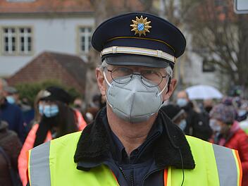 Erster Hauptkommsissar Thomas Baumeister, im Hintergrund demonstrieren Menschen in Bad Kissingen gegen die Corona-Maßnahmen.