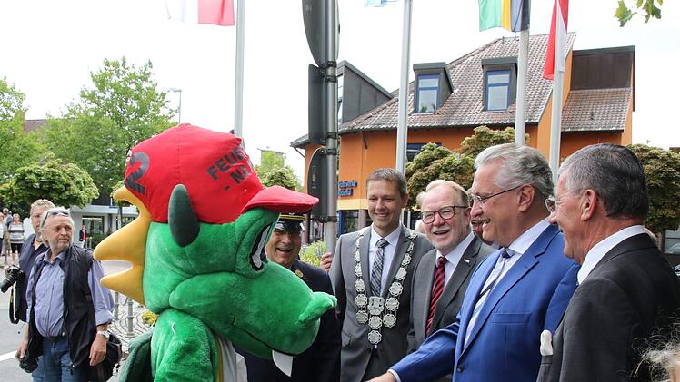 Handschlag mit Löschdrache: Innenminister Joachim Herrmann (Zweiter von rechts) sowie die Ehrengäste wurden von "Löschi", dem bei den Landkreisfeuerwehren entwickelten Maskottchen der Jugendfeuerwehren, empfangen. Fotos: Michael Stelzner