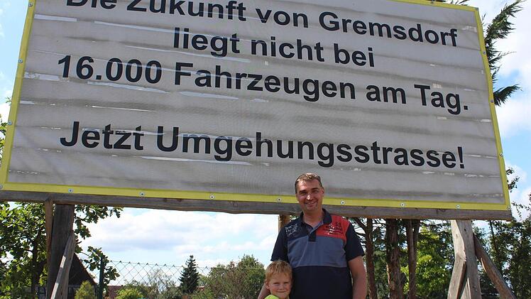 Markus Franke mit seinem Sohn Jakob vor einem der Banner, die die Bürgerinitiative im Ort aufgehängt hat.