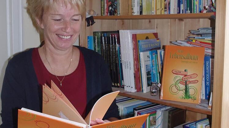 Helga Dietz-Jörg blättert in einem Lebensalbum.   Foto: Heike Schülein