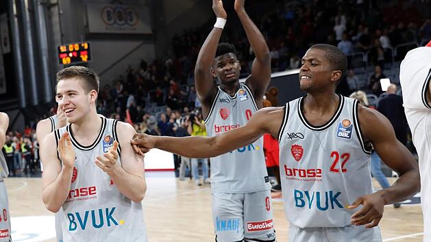 Die W&uuml;rzburger (von links) Nils Ha&szlig;further, Junior Etou und Cameron Wells lassen sich von den Fans feiern. Foto: Daniel L&ouml;b