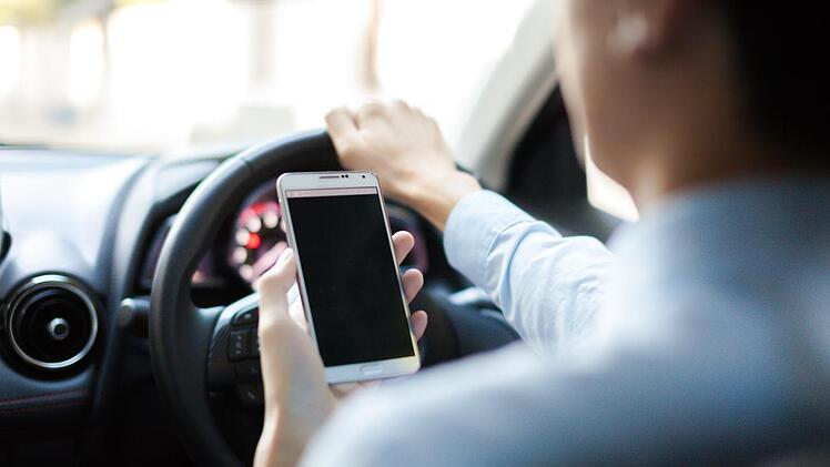 Nur mal kurz die letzte SMS checken oder schnell Zuhause anrufen - und das während der Fahrt. Das kann nicht nur teuer, sondern auch gefährlich werden. Foto: Archiv