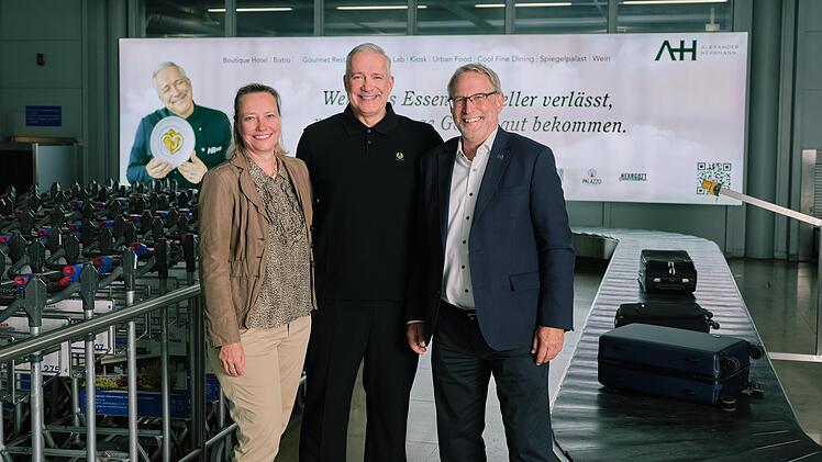 Corinna Sattler, Leitung Marketing; Alexander Herrmann, Sternekoch und Dr. Michael Hupe, Flughafengesch&auml;ftsf&uuml;hrer vor der neuen Werbetafel in der Gep&auml;ckr&uuml;ckgabe am Airport N&uuml;rnberg.