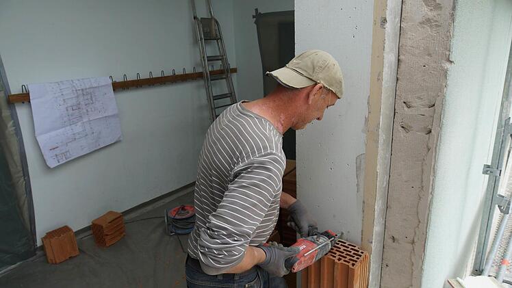 Ein Arbeiter bohrt an der Türlaibung zur künftigen Fluchttreppe.Foto: Arkadius Guzy