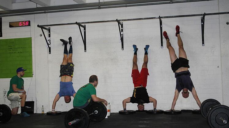 Die Athleten machen sogenannte Handstand-Push-ups - eine harte Übung. Sie begeben sich in den Handstand, beugen dann - während sie auf Händen stehen bleiben - die Arme auf und nieder.  Foto: Sonja Adam