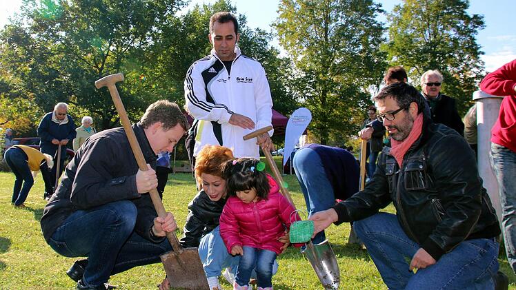 Premiere bei der 5. Krokus-Pflanzaktion im Bad Rodacher Kurpark: Um die 10 000 neuen Zwiebeln in die Erde zu bringen, hatte Bürgermeister Tobias Ehrlicher (links) erstmals auch in der Kurstadt untergebrachte Flüchtlinge um Hilfe gebeten. Die kleine Donya Alipoor sowie ihre Eltern Fatime und Morteza aus dem Iran halfen begeistert mit, auch zur Freude von Stadtrat Rainer Möbus (rechts).Foto: Bettina Knauth