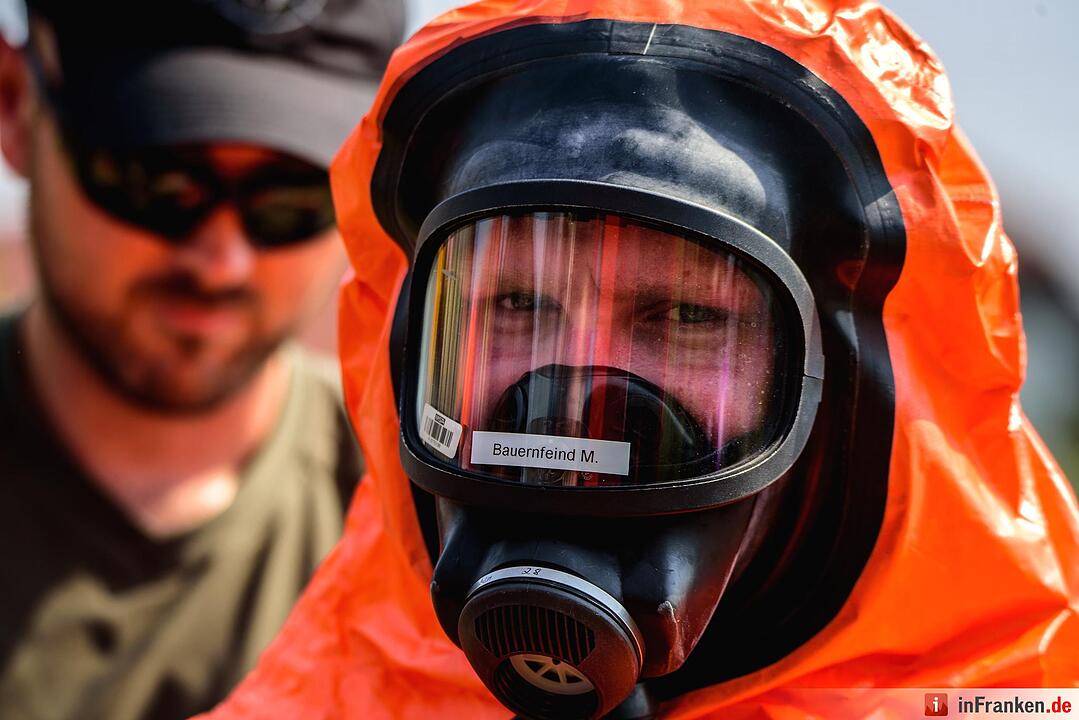 Einsatzkräfte der Feuerwehr ziehen sich am 11.08.2015 in Engelmannsreuth (Bayern) Ganzkörper-Schutzanzüge an. Bei Engelmannsreuth ist ein F-16 Kampfjet der US-Streitkräfte abgestürzt. Foto: Nicolas Armer/dpa