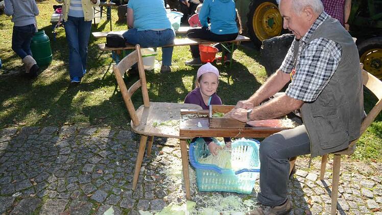 Antonia Fröba holt von Klaus Glatzer den in Scheiben gehobelten Weißkohl als Nachschub zum Einstampfen in die Fässer.