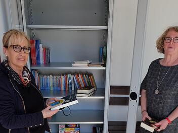 Bürgermeisterin Judith Dekant (links) und Helga Beck (rechts) am neuen Bücherschrank in der Bushaltestelle Rothhausen.