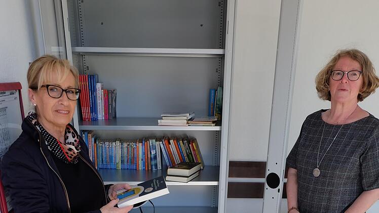 Bürgermeisterin Judith Dekant (links) und Helga Beck (rechts) am neuen Bücherschrank in der Bushaltestelle Rothhausen.