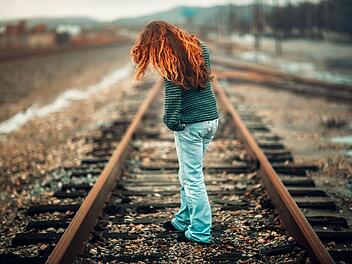 Frau l&auml;uft auf Bahngleisen
