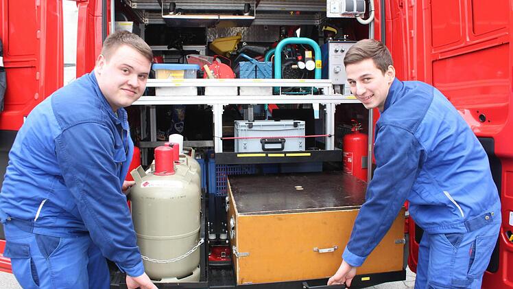 Sebastian Knauer und Tobias Zollnhofer zeigen bei geöffneten Hecktüren des neuen Brandschutzerziehungs-Fahrzeuges, wie die Ausstattung darin sicher verstaut ist. Foto: Popp