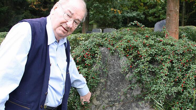 Helmut Marx am Grabstein der Familie Putz. Mittlerweile haben Mitarbeiter des Bauhofes den Findling frei geschnitten und gereinigt, demnächst soll noch die Schrift nachgezeichnet werden.  Fotos: Ralf Ruppert/Helmut Marx